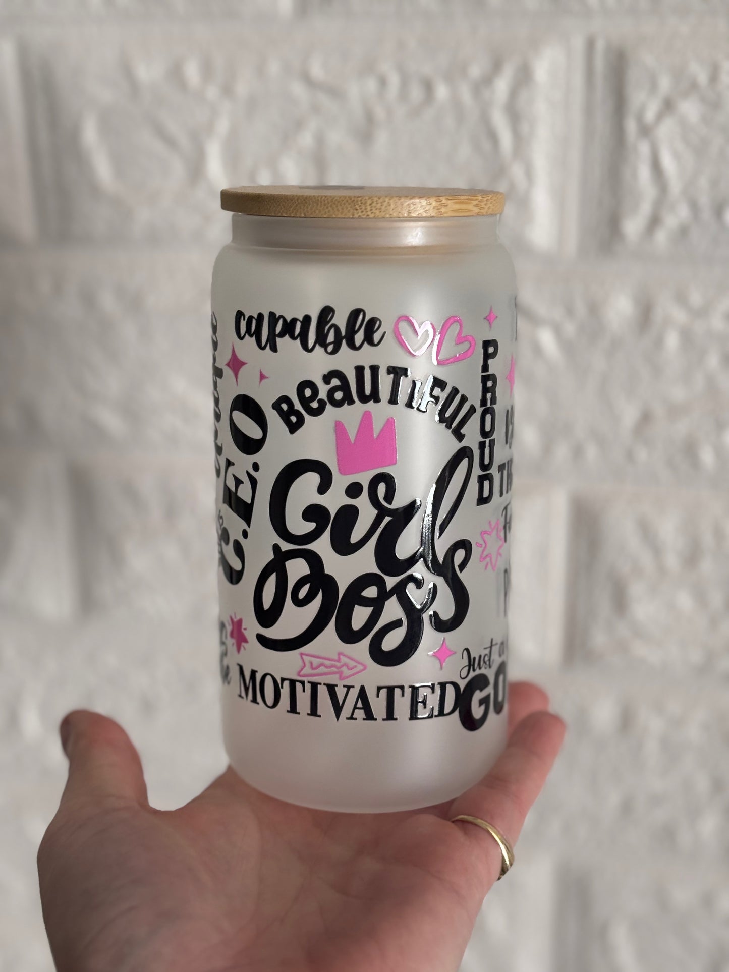 Een matglazen drinkbeker met bamboe deksel vast. De beker is bedrukt met inspirerende woorden zoals 'Girl Boss; 'Motivated; 'Beautiful' en 'Capable' in zwarte en roze letters, samen met kleine decoratieve hartjes en een kroon.