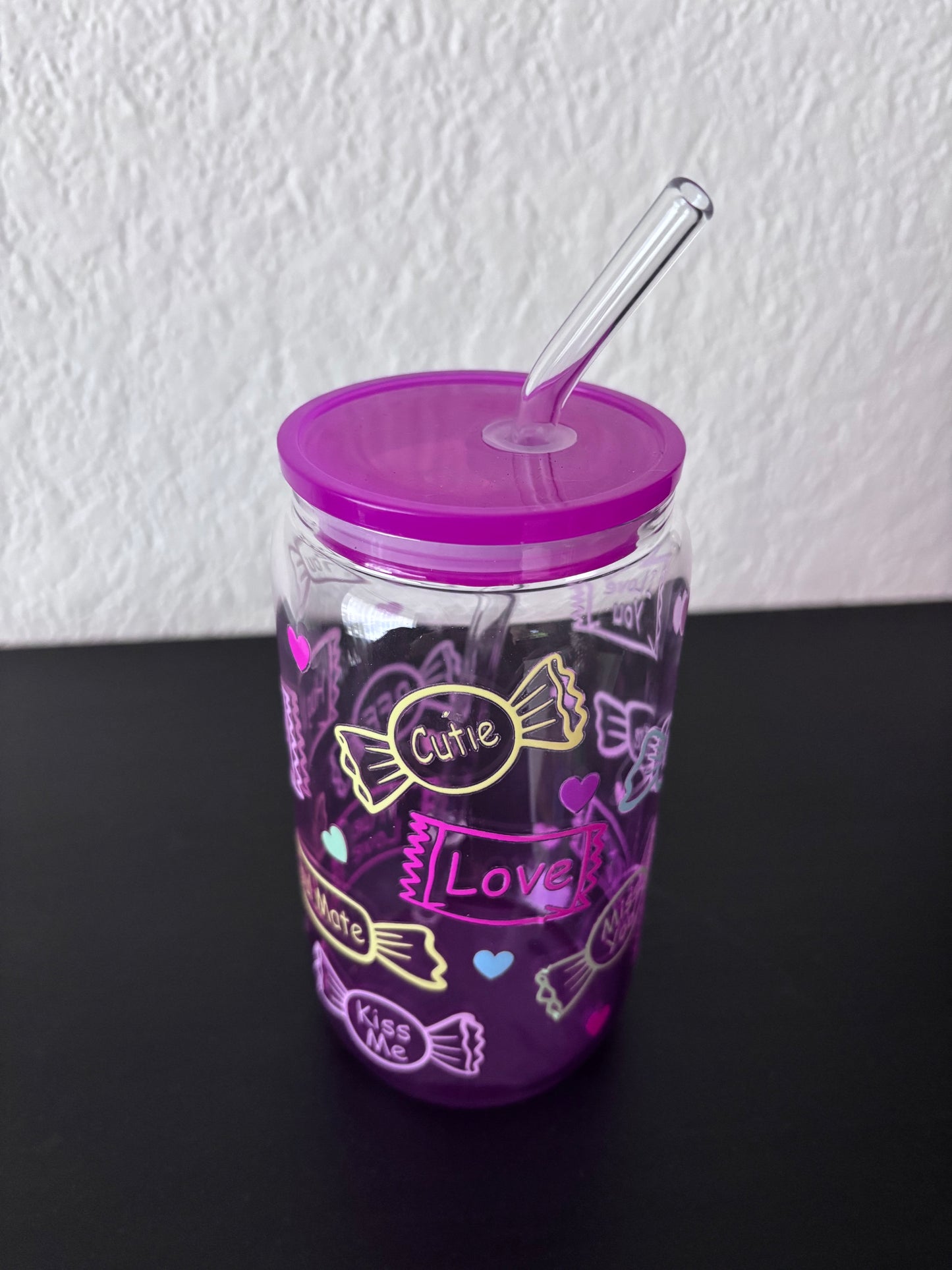 Paarse drinkbeker met transparant rietje, versierd met snoepjes en teksten als “Cutie”, “Love” en “Kiss Me”,