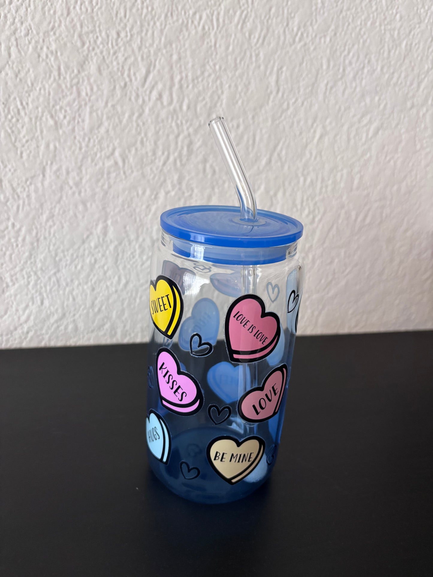 Blauwe drinkbeker met transparant rietje, versierd met kleurrijke hartjes met teksten als “Love”, “Sweet”, “Kisses” en “Be Mine