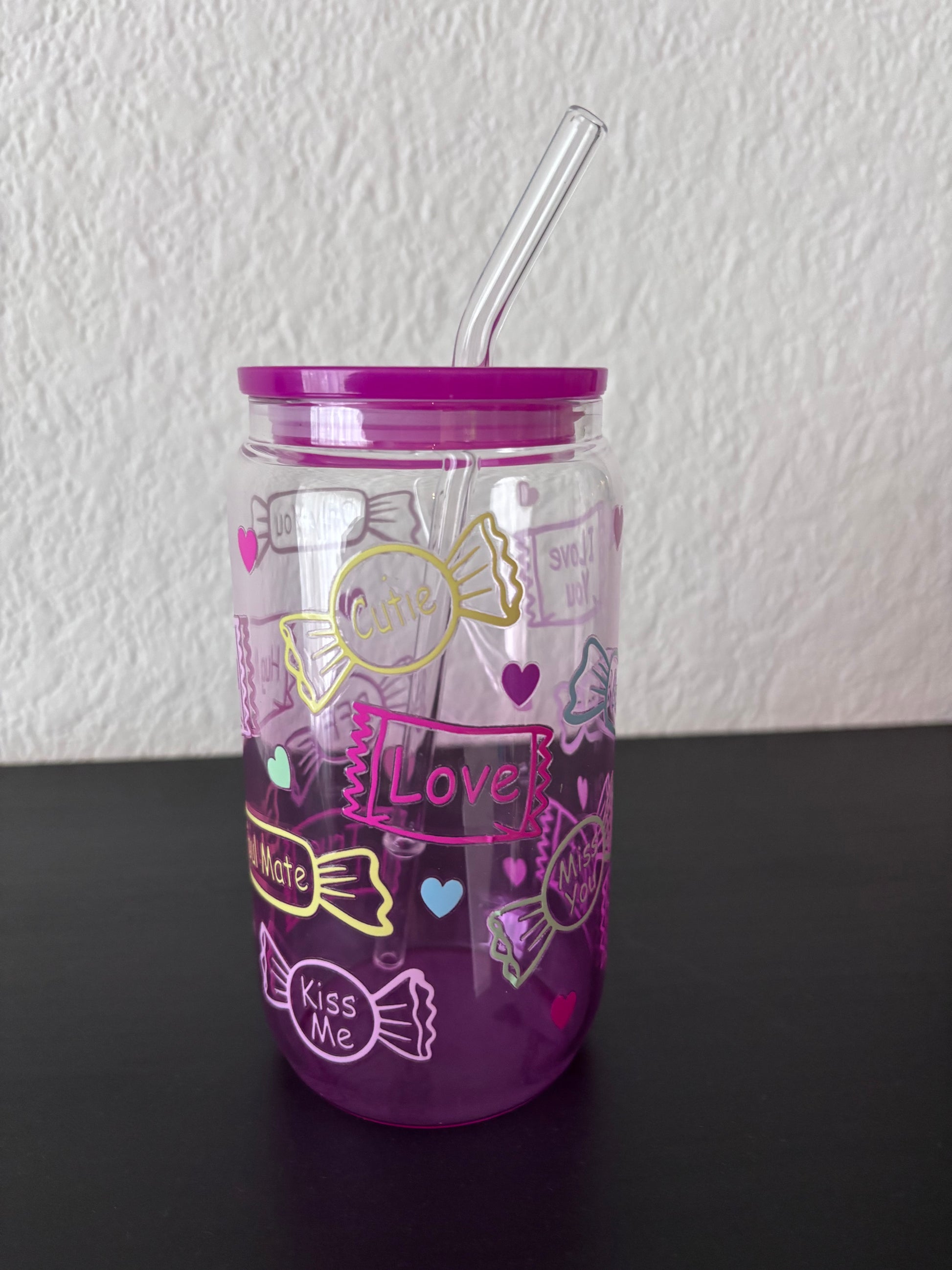 Paarse drinkbeker met transparant rietje, versierd met snoepjes en teksten als “Cutie”, “Love” en “Kiss Me”,