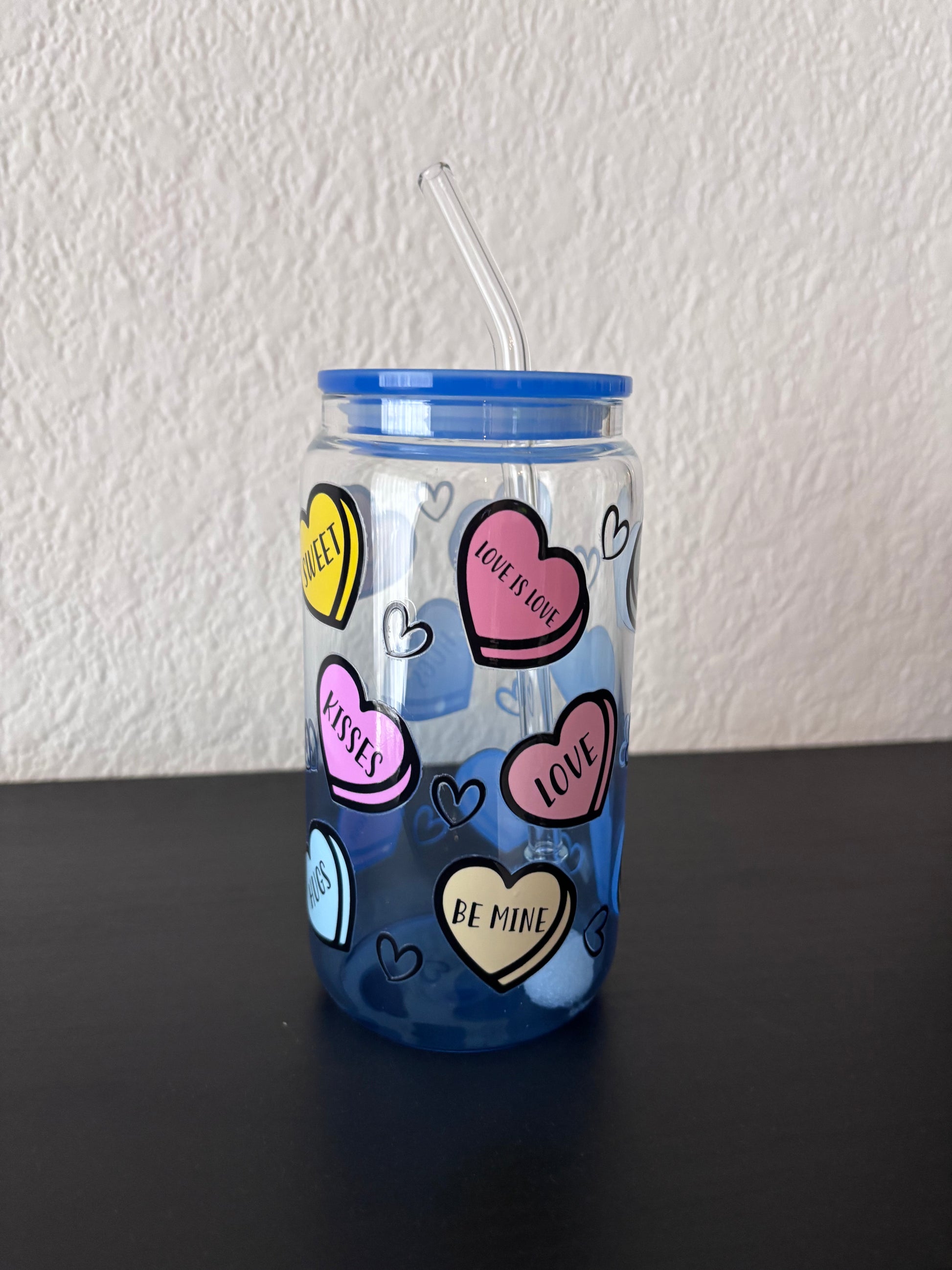 Herbruikbare beker met blauw deksel en hartjesdesign in pastelkleuren.
